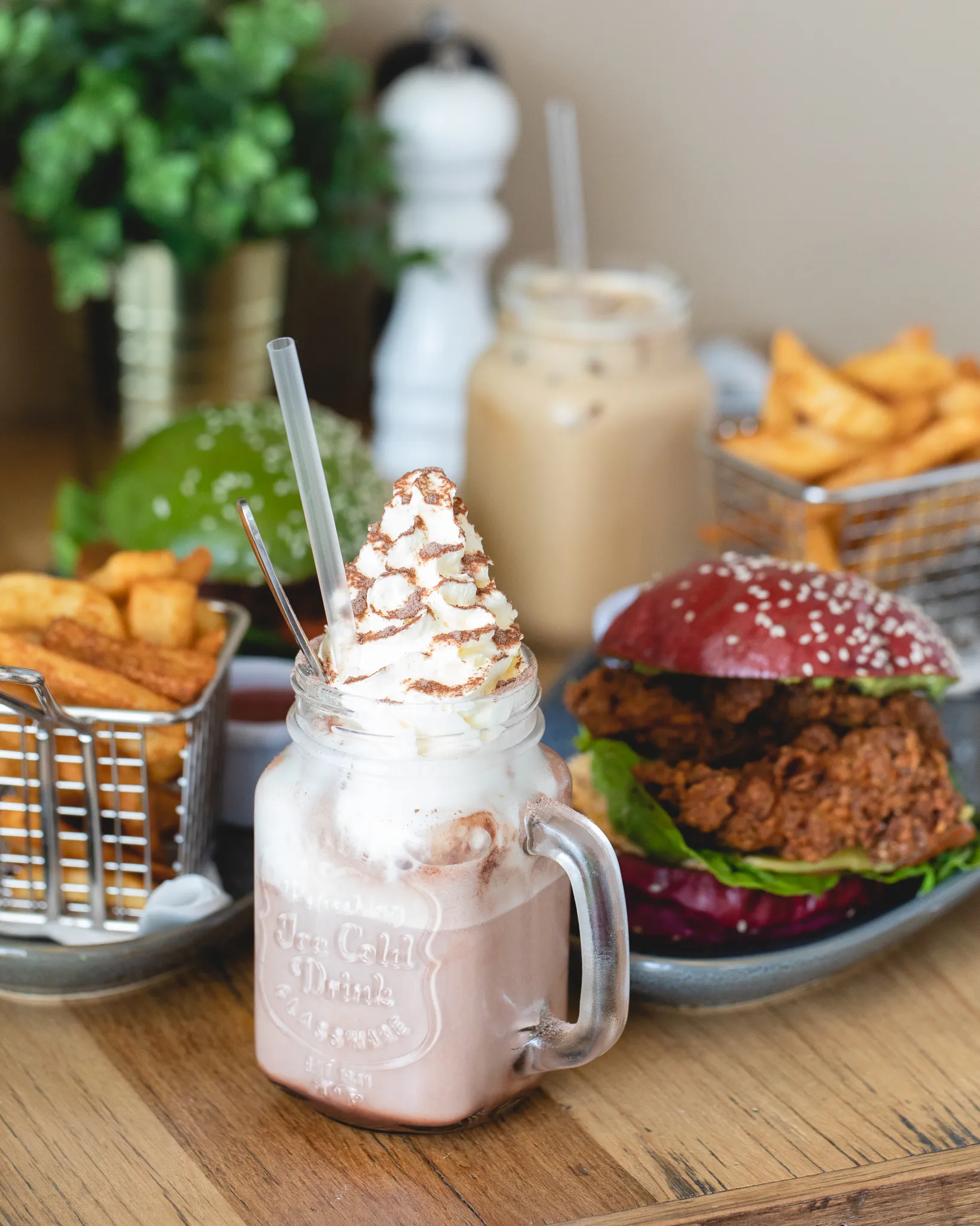 Chocolate milkshake, chicken burger and fries on a wooden table