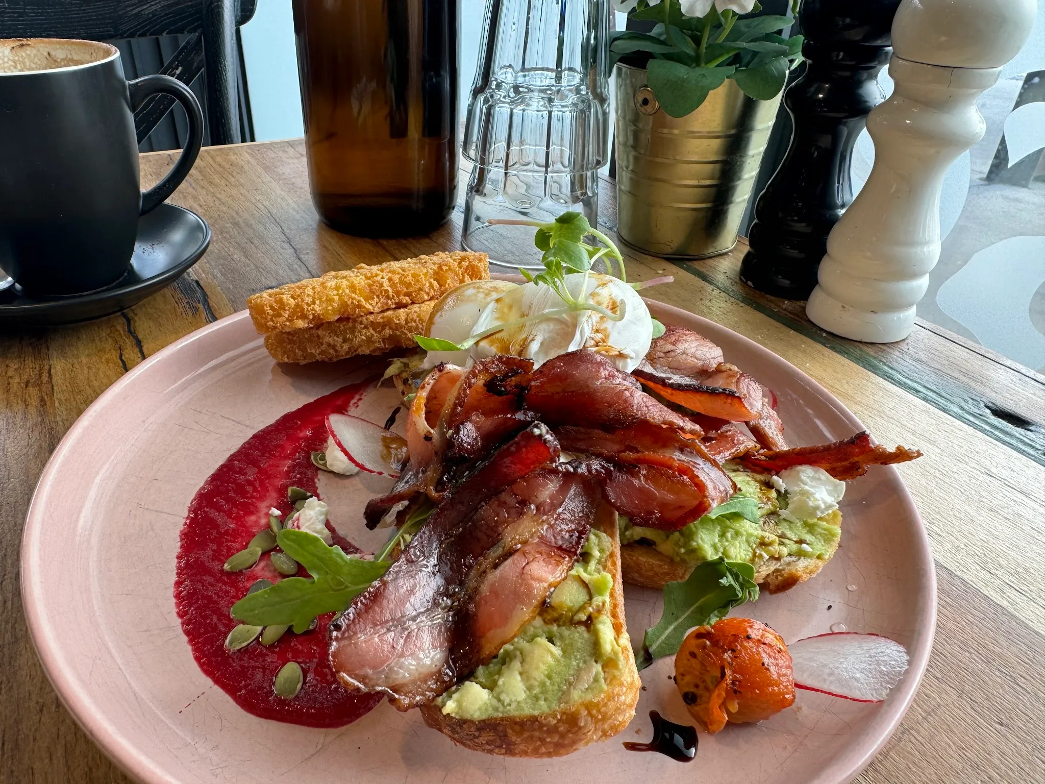 Brunch plate with poached eggs, bacon, avocado toast and beetroot puree
