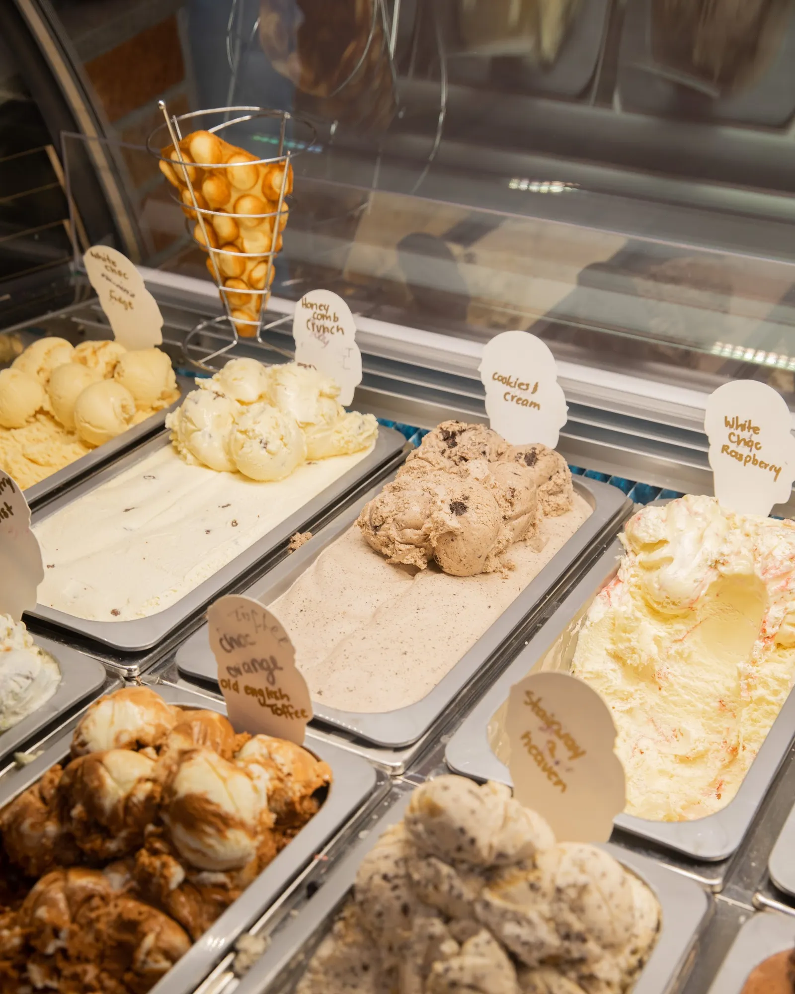 Gelato display case with assorted flavours and hand-written labels