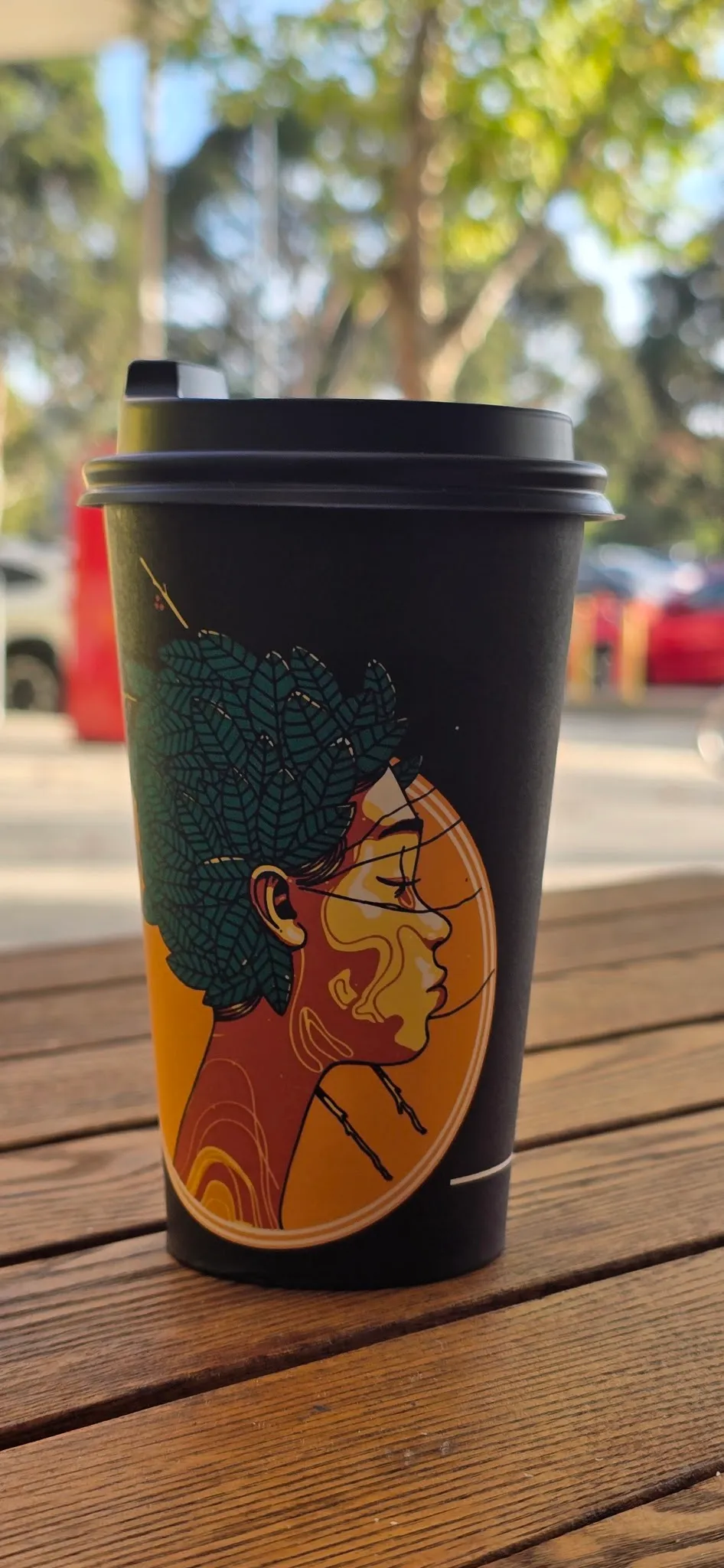 Branded Homestead Cafe takeaway coffee cup on outdoor table