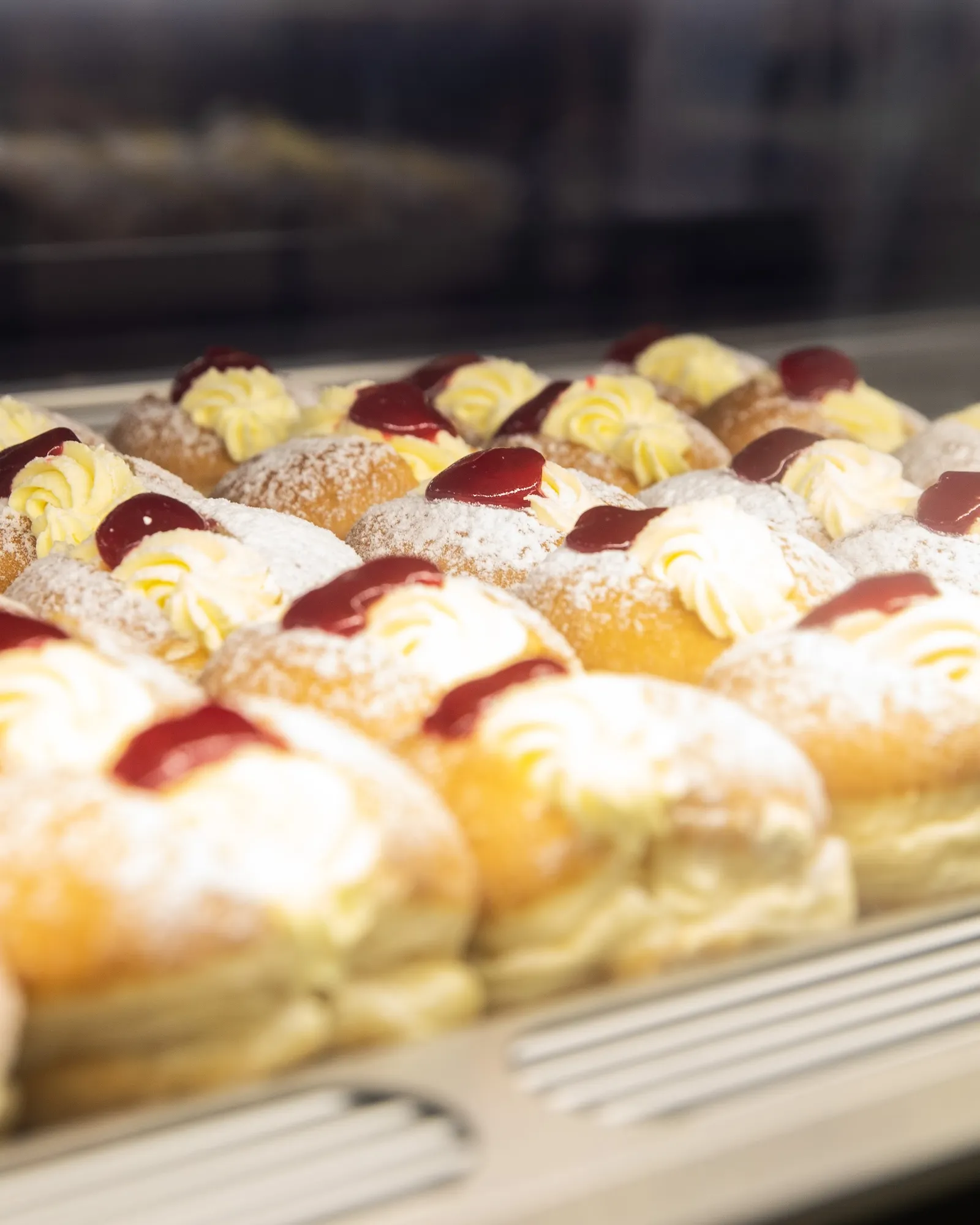 Rows of cream and jam-filled doughnuts in bakery display